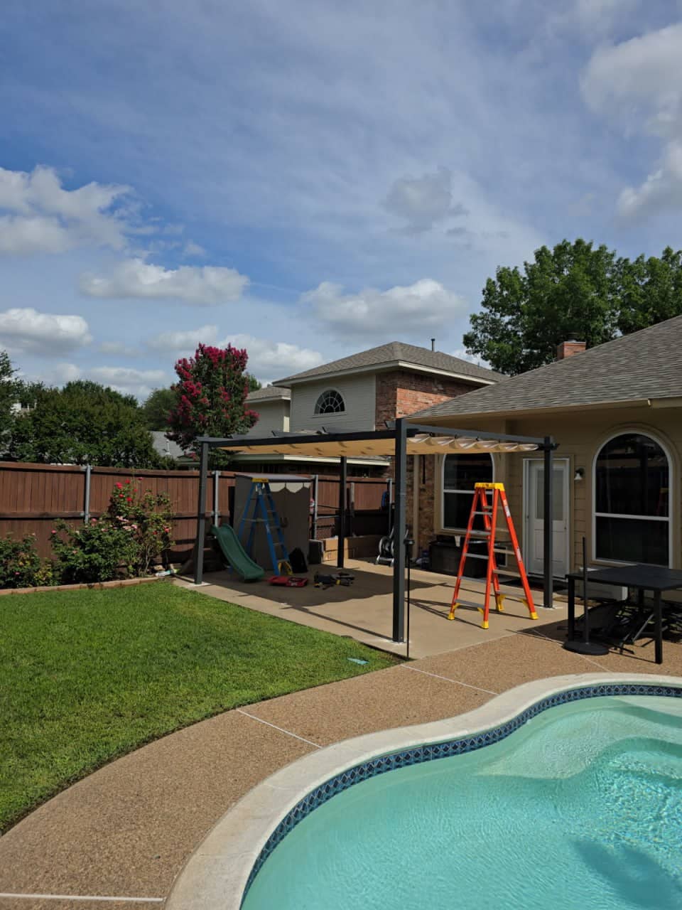 Modern louvered pergola with privacy wall installed on a paver patio in a backyard