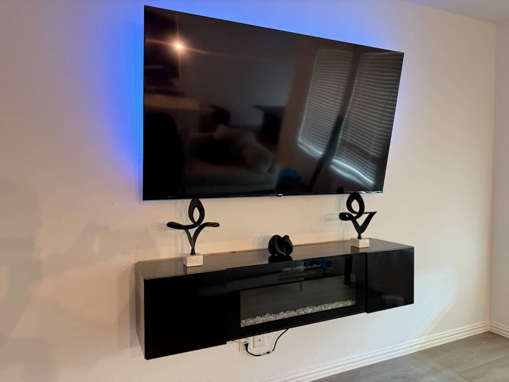 Large flat-screen TV securely wall-mounted in a bedroom above a dresser