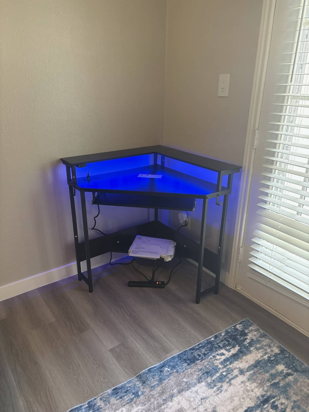 Corner desk with LED lighting and built-in shelving assembled in a home office