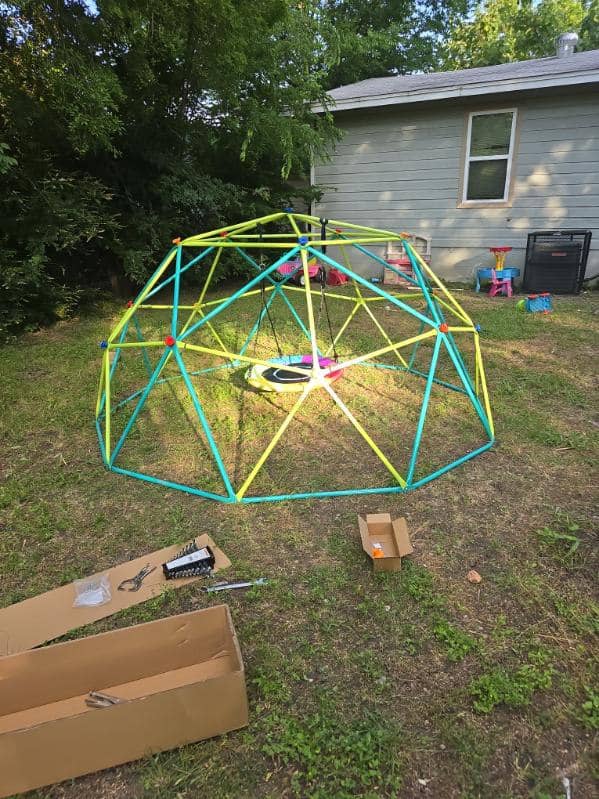 Colorful geodesic dome climber with swing assembled in a backyard for kids
