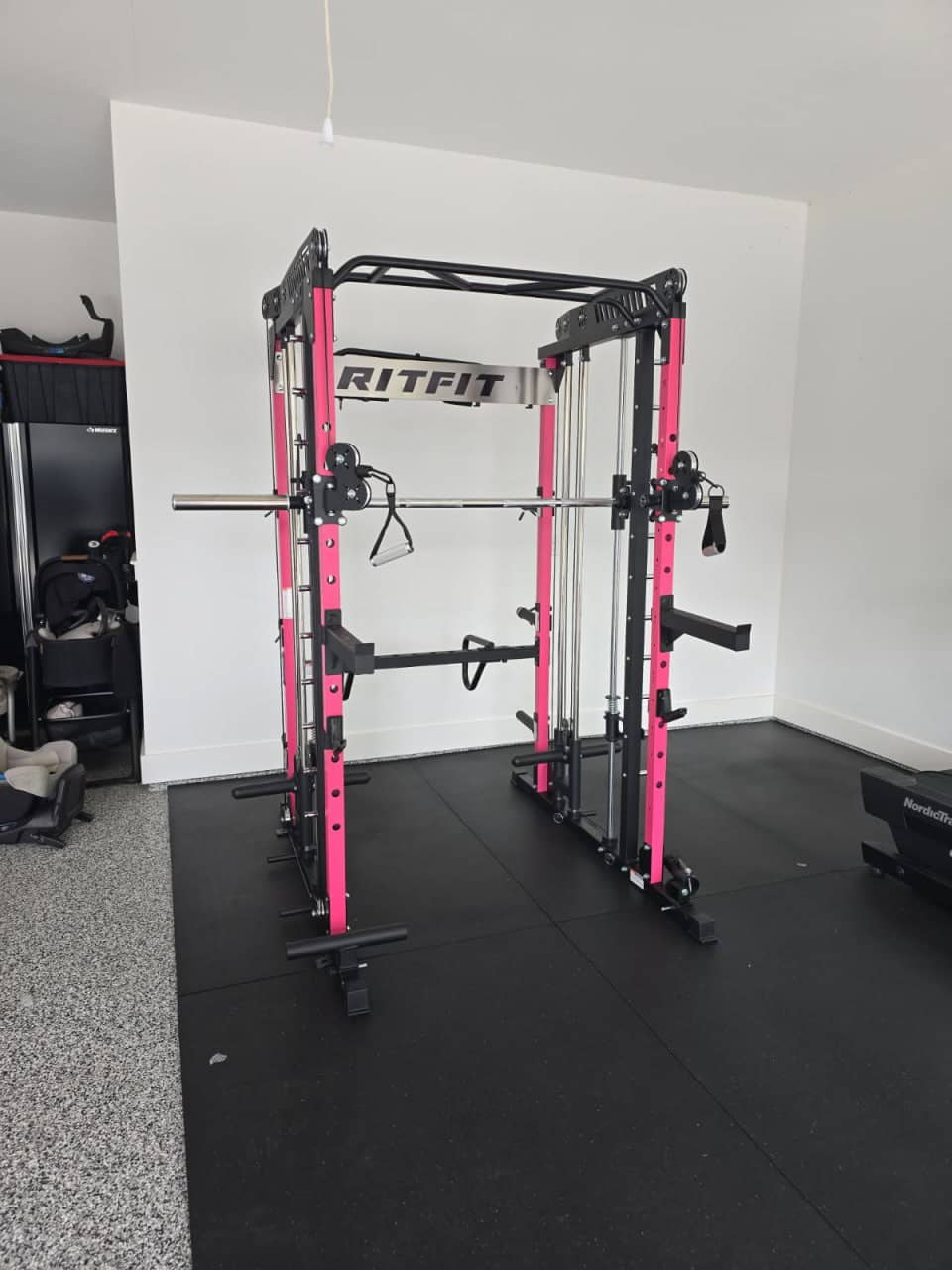 Full power cage with weight plates, bench, and dumbbell rack assembled in a home gym